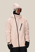 A person wears the 686 Men's Hydra™ Thermagraph® Jacket by 686 with a pink beanie, black gloves, black neck gaiter, and reflective ski goggles, standing against a plain beige background.