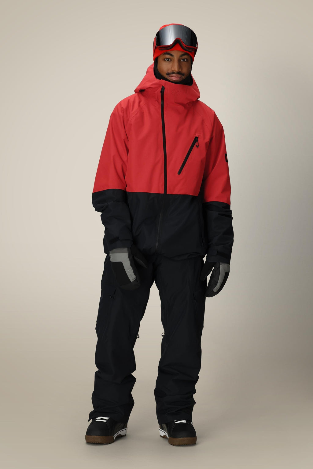 A person in a 686 Men's Hydra™ Thermagraph® Jacket by 686, black snow pants, gray gloves, black snow boots, and red ski goggles stands facing forward against a neutral background.