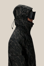 A person in profile wears the 686 Men's SMARTY® 3-In-1 Rodeo™ 3L Jacket with the hood up and black ski goggles, set against a plain beige background.