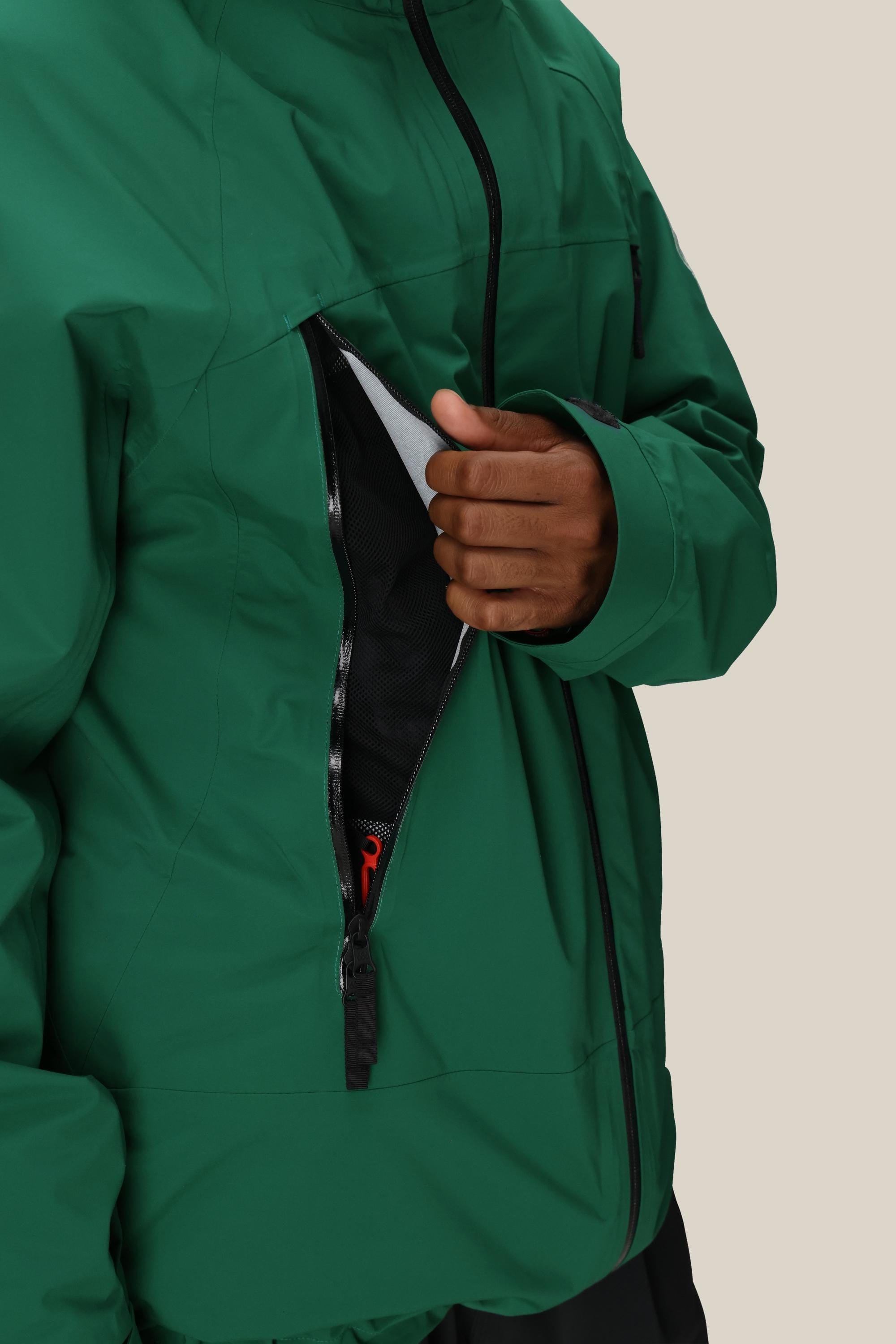 A man wearing the 686 Men's SMARTY® 3-In-1 Rodeo™ 3L Jacket unzips a large chest pocket, exposing a black mesh lining with a hint of red inside. The background is plain beige.