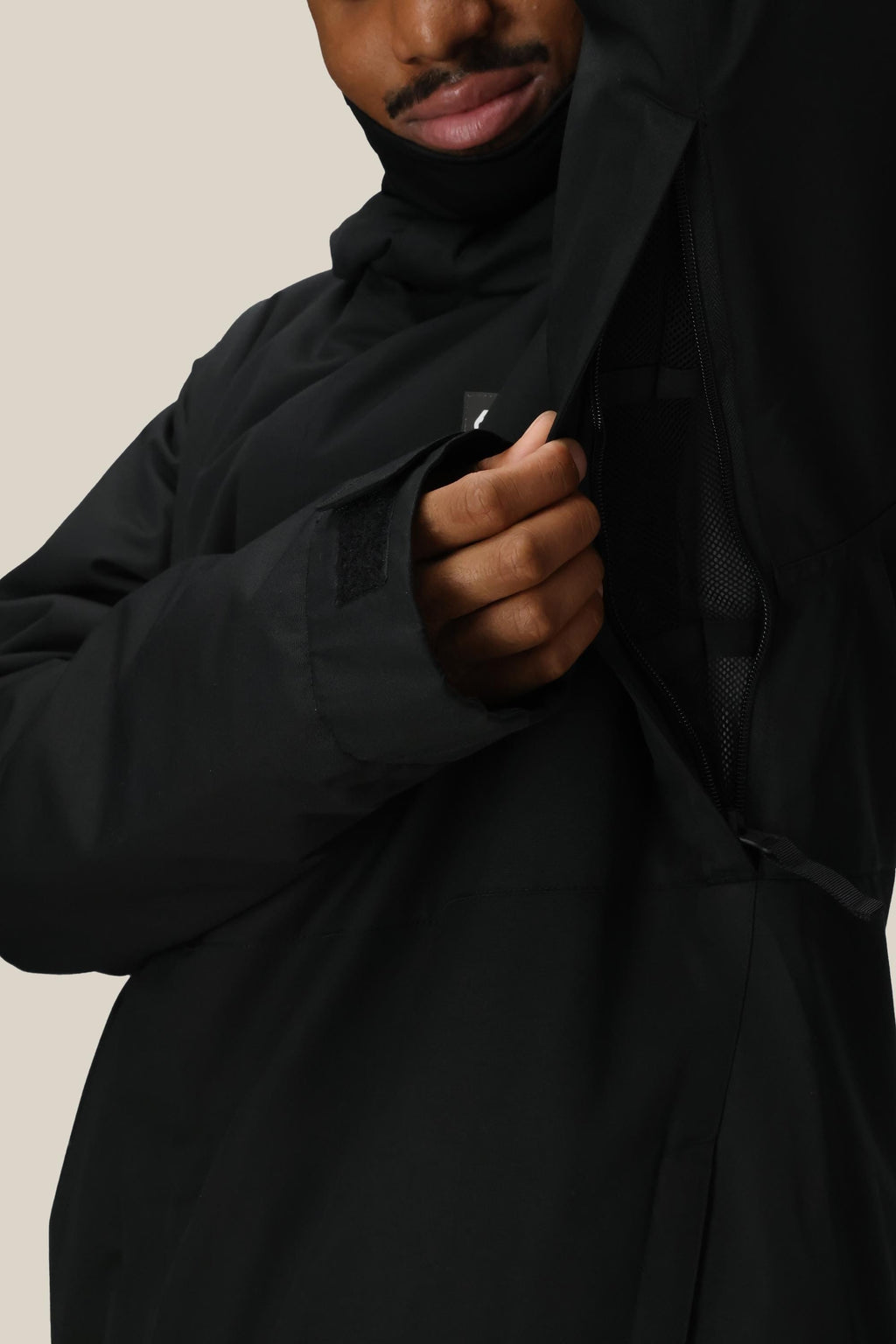 A person in a 686 Men's Foundation™ Insulated Jacket by 686 unzips a large side vent, revealing mesh lining. Only the lower half of their face is visible.