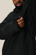 A person in a 686 Men's Foundation™ Insulated Jacket by 686 unzips a large side vent, revealing mesh lining. Only the lower half of their face is visible.