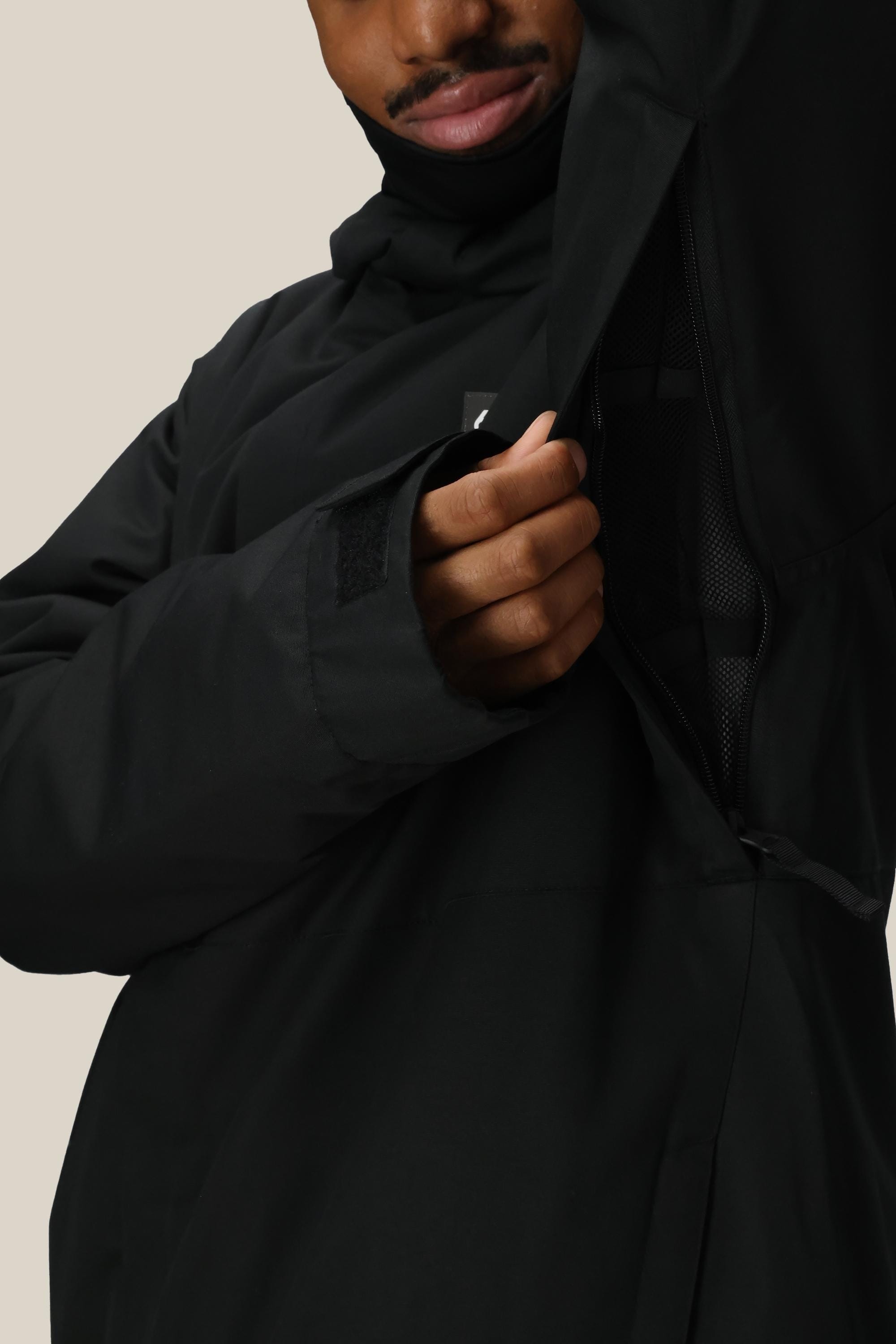 A person in a 686 Men's Foundation™ Insulated Jacket by 686 unzips a large side vent, revealing mesh lining. Only the lower half of their face is visible.