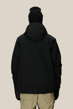 A person is shown from the back against a plain light background wearing the 686 Men's Foundation™ Insulated Jacket, a black hooded polyester jacket by 686, paired with a black beanie, black gloves, and beige pants.