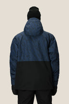 A person is shown from the back against a plain light background, wearing black pants, a black beanie, black gloves, and the 686 Men's Foundation™ Insulated Jacket by 686 in blue and black with a subtle pattern.