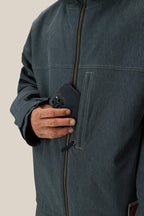 A person places a black smartphone into the zippered chest pocket of a partially zipped 686 Dojo® Jacket, with focus on the hand, phone, and pocket.