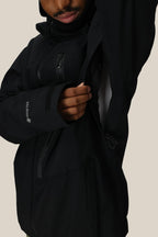 A person in the 686 Men's GORE-TEX GT Thermagraph® Jacket by 686 unzips the underarm vent, showing a white inner layer. Their face is partly visible, with a plain beige background.