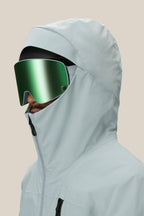 A person wearing the 686 Men's GORE-TEX GT Thermagraph® Jacket in light gray and large reflective green ski goggles faces left against a plain beige background.
