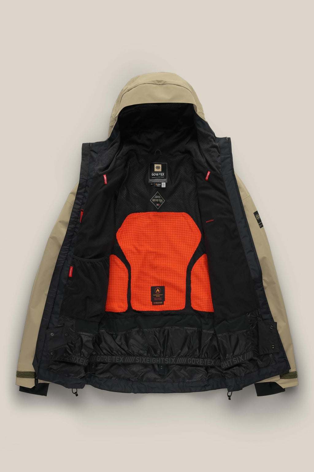 The 686 Men's GORE-TEX GT Thermagraph® Jacket in tan features a black interior with an orange mesh back panel, showcasing GORE-TEX and 686 branding. This waterproof jacket offers adjustable cuffs and inner pockets for added functionality.