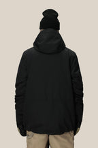 A person facing away, wearing a black beanie, beige pants, light gloves, and the 686 Men's SMARTY® 3-In-1 Form Jacket with a hood by 686, stands against a plain light background.