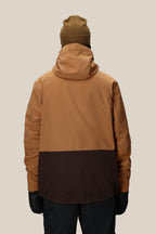 A person wearing the 686 Men's SMARTY® 3-In-1 Form Jacket in brown and tan, black gloves, black pants, and a tan beanie stands with their back to the camera against a plain beige background.