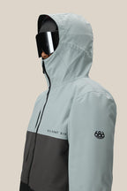 A man models the 686 Men's SMARTY® 3-In-1 Form Jacket in light gray and black with SIX EIGHT SIX lettering and sleeve logo, paired with large black ski goggles, against a beige background. This waterproof polyester jacket is both stylish and functional.