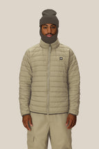 A person wears the 686 Men's SMARTY® 3-In-1 Form Jacket in light beige, paired with matching pants and a gray balaclava, standing against a plain light background and looking directly at the camera with a neutral expression.