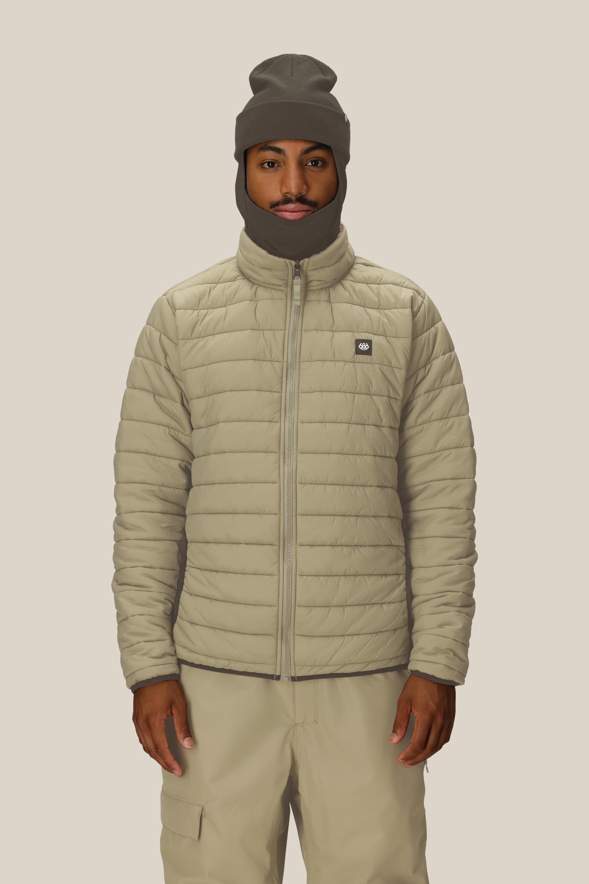 A person wears the 686 Men's SMARTY® 3-In-1 Form Jacket in light beige, paired with matching pants and a gray balaclava, standing against a plain light background and looking directly at the camera with a neutral expression.