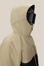 A person wearing the 686 Men's SMARTY® 3-In-1 Form Jacket in tan with a hood and large black ski goggles, facing right with their face partially covered by the jacket and goggles.