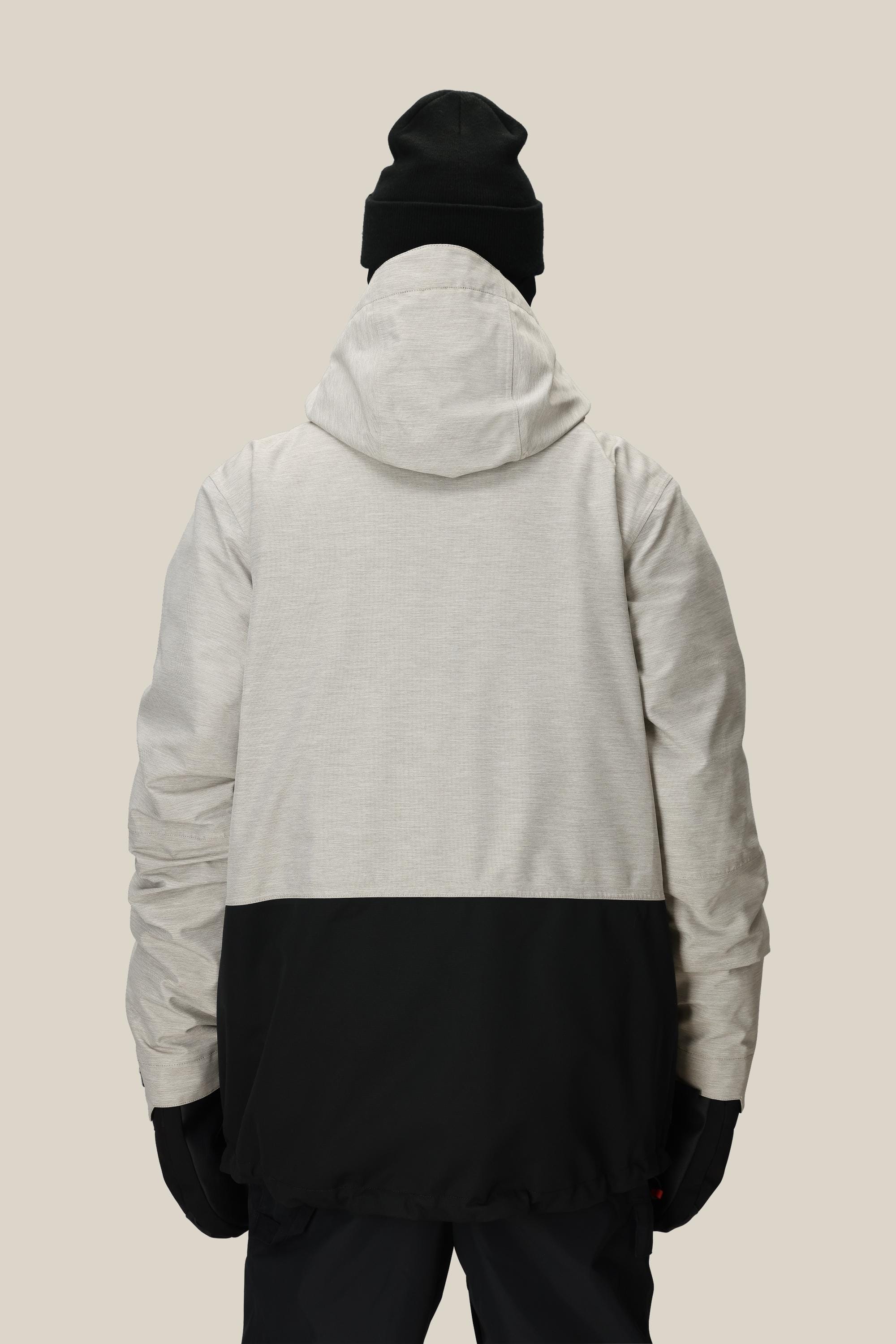 A person wearing the 686 Men's SMARTY® 3-In-1 Form Jacket—featuring a light gray top half and black bottom half—plus a black beanie and gloves, is seen from the back against a plain beige background.