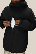 A person in the 686 Mens GORE-TEX Core Shell Jacket opens a zippered chest pocket, revealing a white inner layer. Only the lower face is visible against a plain, light background.