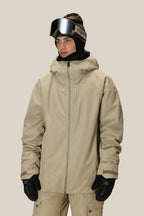 A person wearing the 686 Mens Gateway Shell Jacket in beige, matching pants, black gloves, a black neck warmer, a dark beanie, and ski goggles stands against a plain light background.
