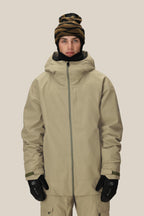 A person wears the 686 Mens Gateway Shell Jacket in tan with matching pants, black gloves, and a black and brown patterned beanie, standing facing forward against a plain light background.