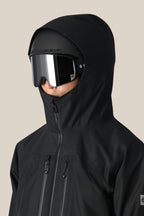 A person wearing the 686 Men's GORE-TEX 3L ATV Thermagraph® Jacket with the hood up and large, reflective ski goggles faces slightly right against a plain beige background.