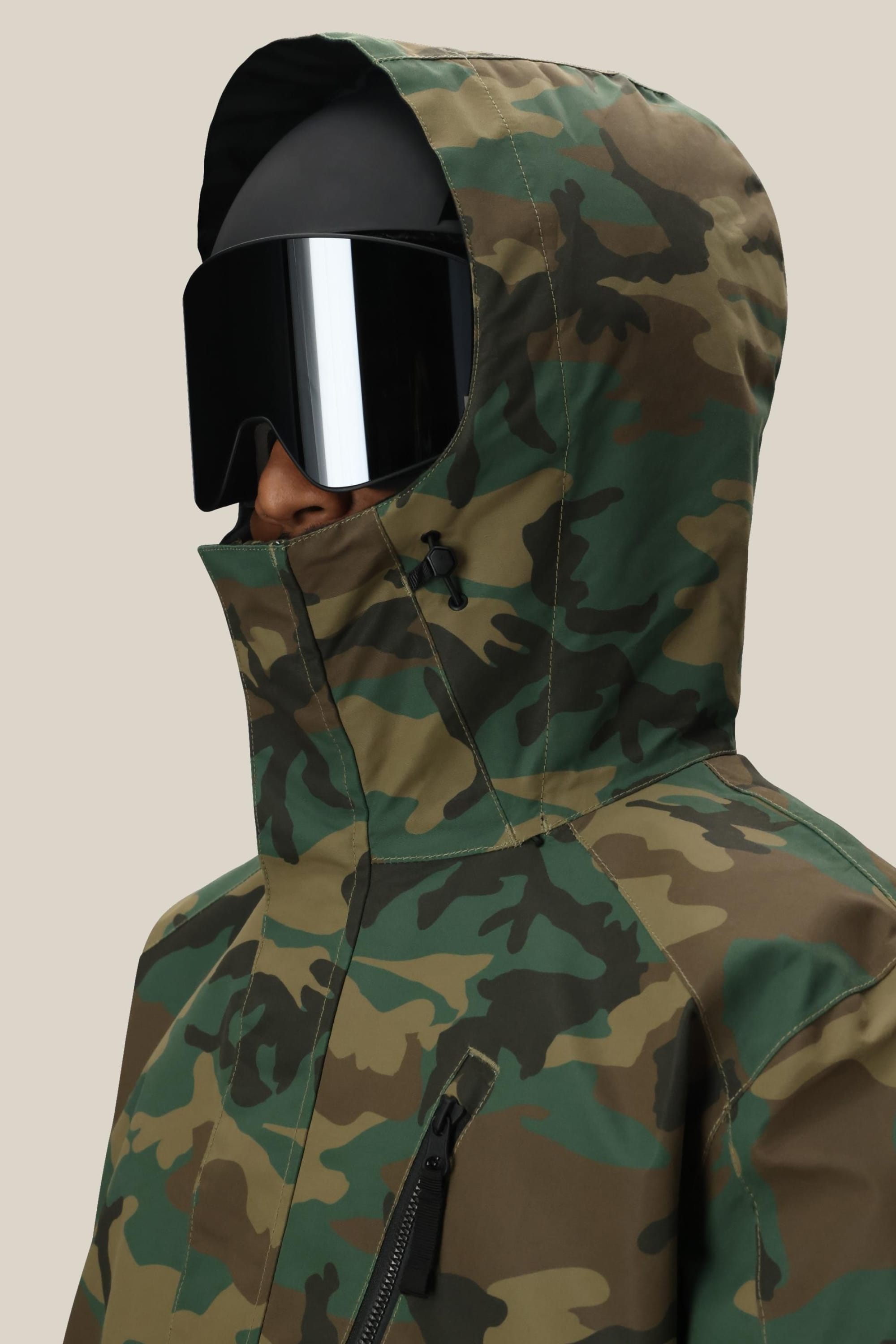 A person wears the 686 Men's Nightline™ Insulated Jacket with the hood up and large, reflective black ski goggles, set against a plain beige background.