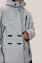 A man fastens the velcro flap on a large front pocket of the 686 Men's Nightline™ Insulated Jacket, featuring a light gray color with black zipper and velcro accents by 686.
