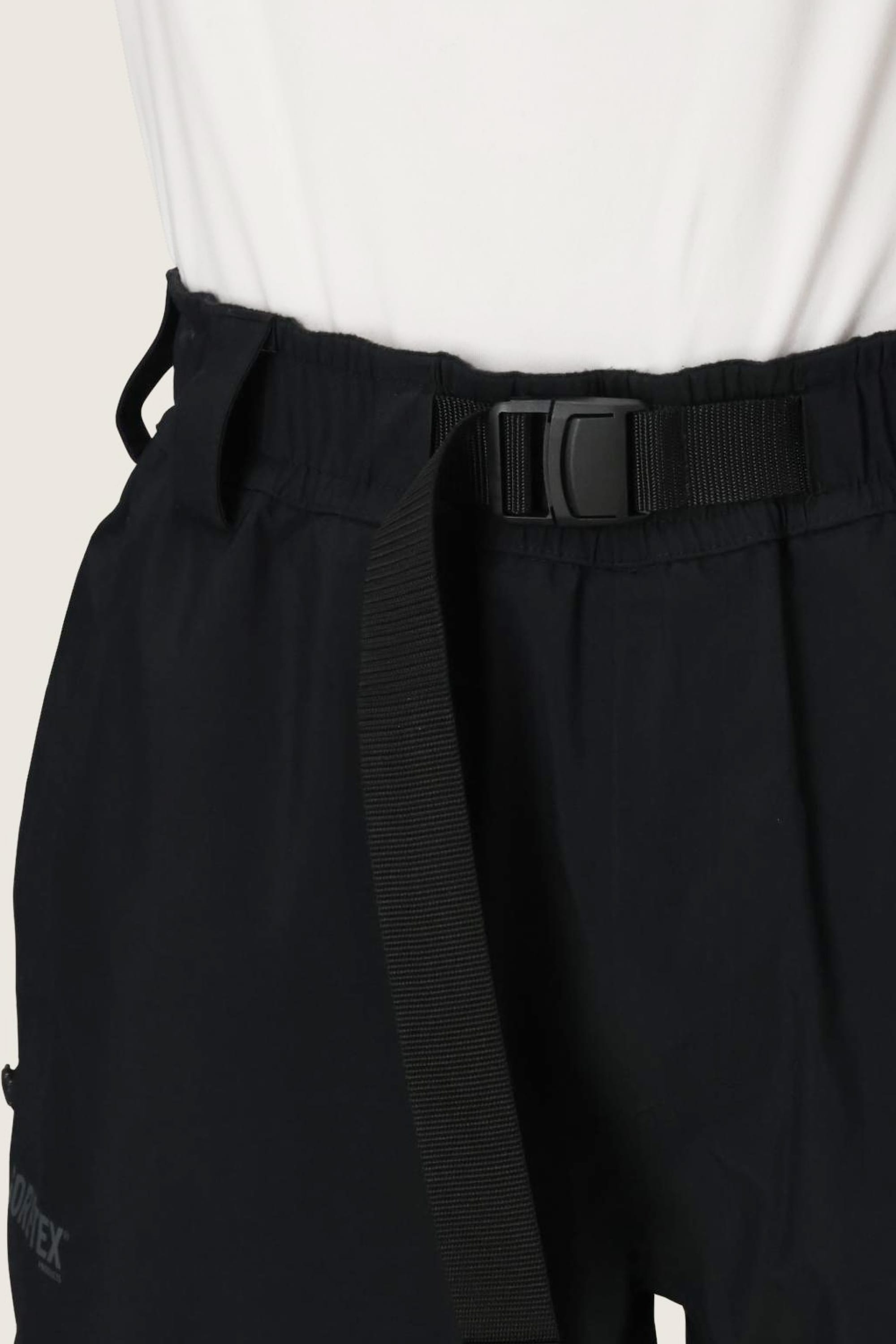 Close-up of a person wearing 686 Dojo® GORE-TEX Pant by 686, featuring an adjustable black webbing belt with a black plastic buckle, paired with a white top.