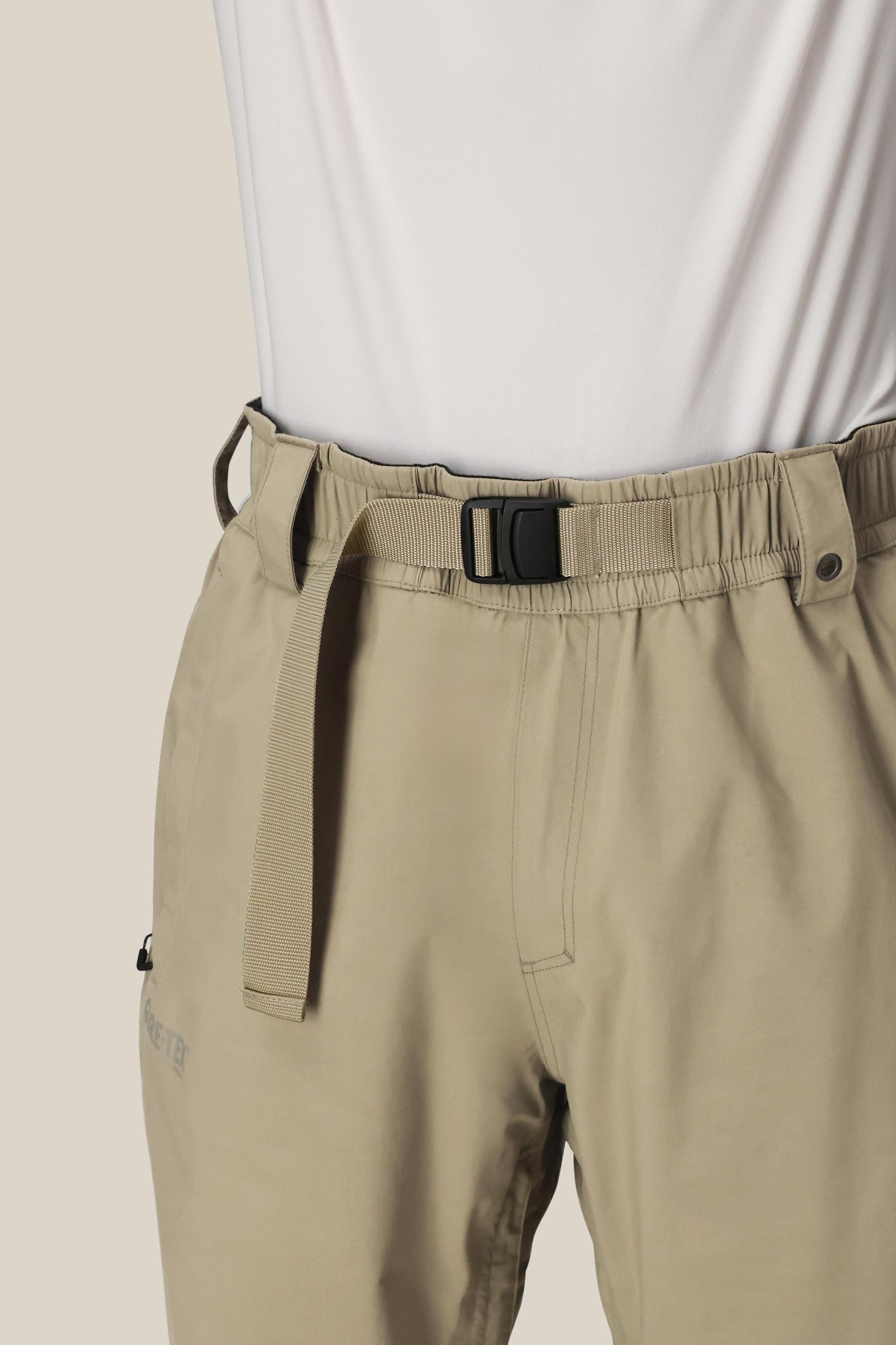 A person wears light beige 686 Dojo® GORE-TEX Pants with an integrated adjustable belt and a white shirt, shown from waist to mid-thigh against a plain background.