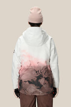 A person stands with their back to the camera, wearing a light pink beanie, brown pants, black gloves, and the 686 Women's Hydra™ Thermagraph® Jacket by 686 in white and pink patterns, set against a plain beige background.