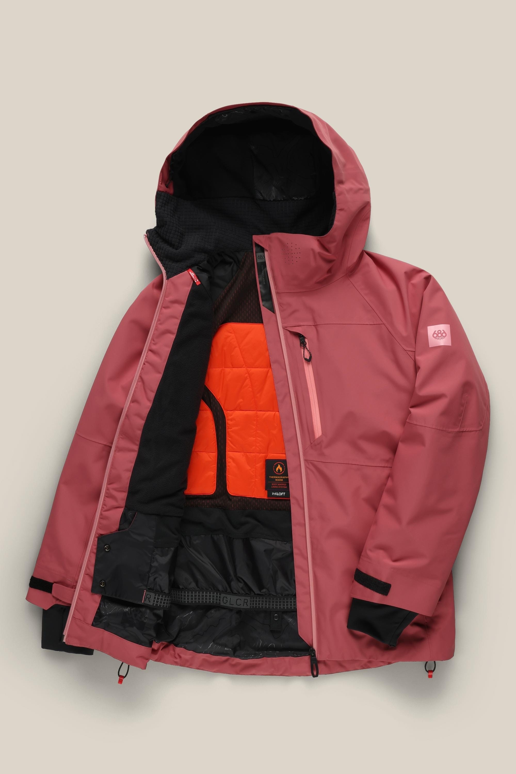 The 686 Women's Hydra™ Thermagraph® Jacket by 686, in rose pink with a hood, zip front, orange quilted lining, black mesh pockets, and adjustable cuffs, is shown against a light beige background.