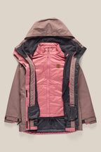 The 686 Women's SMARTY® 3-In-1 Spellbound Jacket by 686 is shown unzipped, revealing its quilted light pink inner layer and stand-up collar, with a brown logo patch on the chest, all set against a beige background.