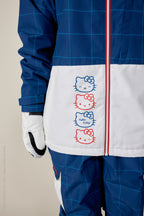 A person wears the 686 Women's Athena™ Insulated Jacket, a blue and white polyester waterproof jacket with red zippers. It features three vertically stacked Hello Kitty faces in red and blue outlines and the text Hello Kitty; only lower half and left arm are visible.