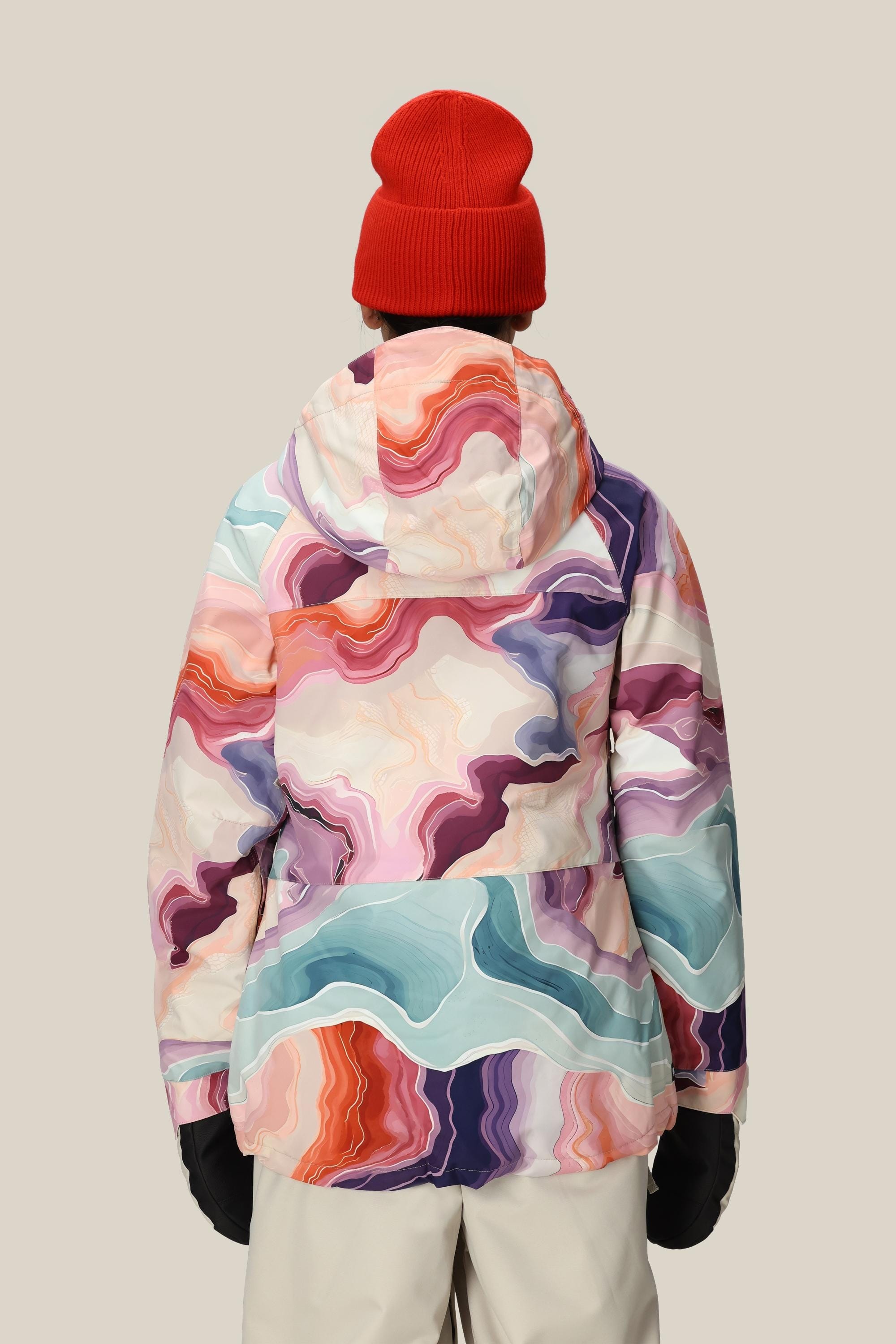 A person shown from behind wears the 686 Women's Athena™ Insulated Jacket with a colorful abstract pattern, paired with a red beanie, black gloves, and light-colored pants against a plain beige background.