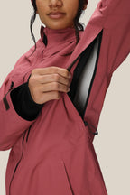 A woman in the 686 Women's GORE-TEX Skyline Thermagraph® Jacket unzips an underarm vent to reveal the lining. Her face is partially visible as she stands against a plain background.