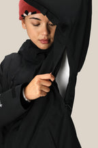 A person wearing the 686 Women's GORE-TEX Willow™ Insulated Jacket in black and a red beanie opens an underarm zipper, highlighting the jacket's ventilation feature.