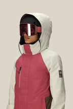 A woman in the 686 Women's GORE-TEX Willow™ Insulated Jacket, wearing a black ski helmet and large red ski goggles, stands against a plain light background.