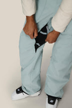 A person wearing 686 Women's Black Magic™ Insulated Bib snow pants opens a zippered vent on the side, revealing black mesh fabric beneath.