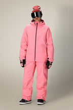 A person wearing a bright pink winter jacket, 686 Women's Aura™ Insulated Cargo Pant by 686, black gloves and shoes, a pink beanie with a white pattern, and large reflective ski goggles stands against a plain background.