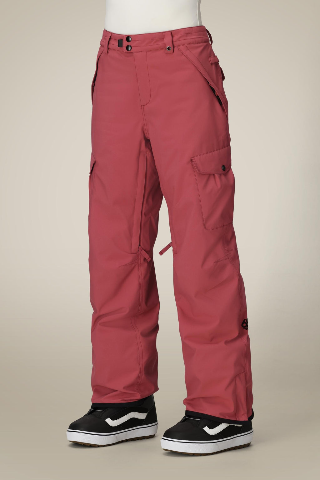 A person wearing 686 Women's Aura™ Insulated Cargo Pant in rose red and black-and-white Vans sneakers stands against a plain beige background, with only their lower body visible.