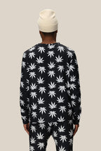 A person wearing the 686 Men's HUF Plantlife Base Layer LS Top stands facing away from the camera against a plain beige background.