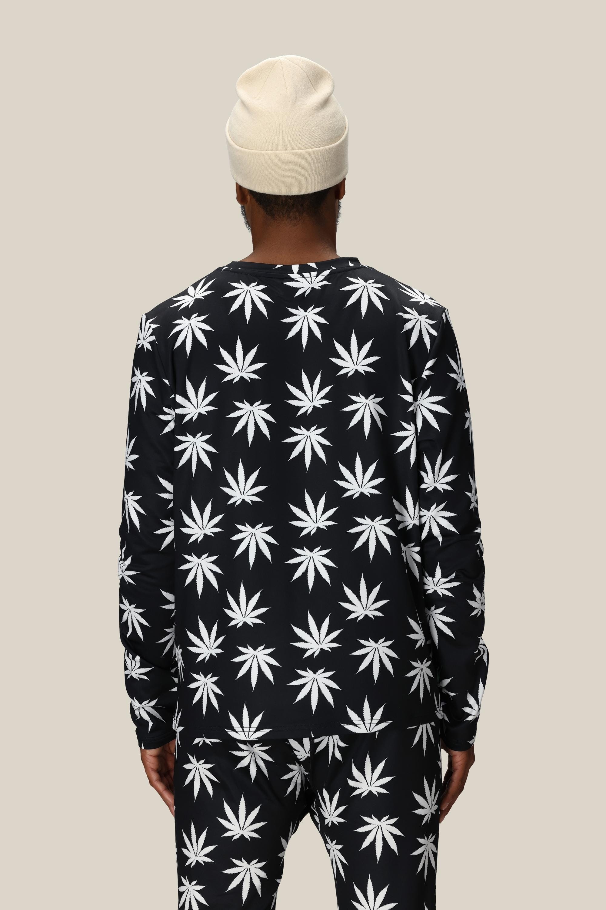 A person wearing the 686 Men's HUF Plantlife Base Layer LS Top stands facing away from the camera against a plain beige background.