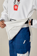 A person in blue checkered pants unzips their 686 Women's Hello Kitty® Waterproof Hoody, revealing the white interior lining.