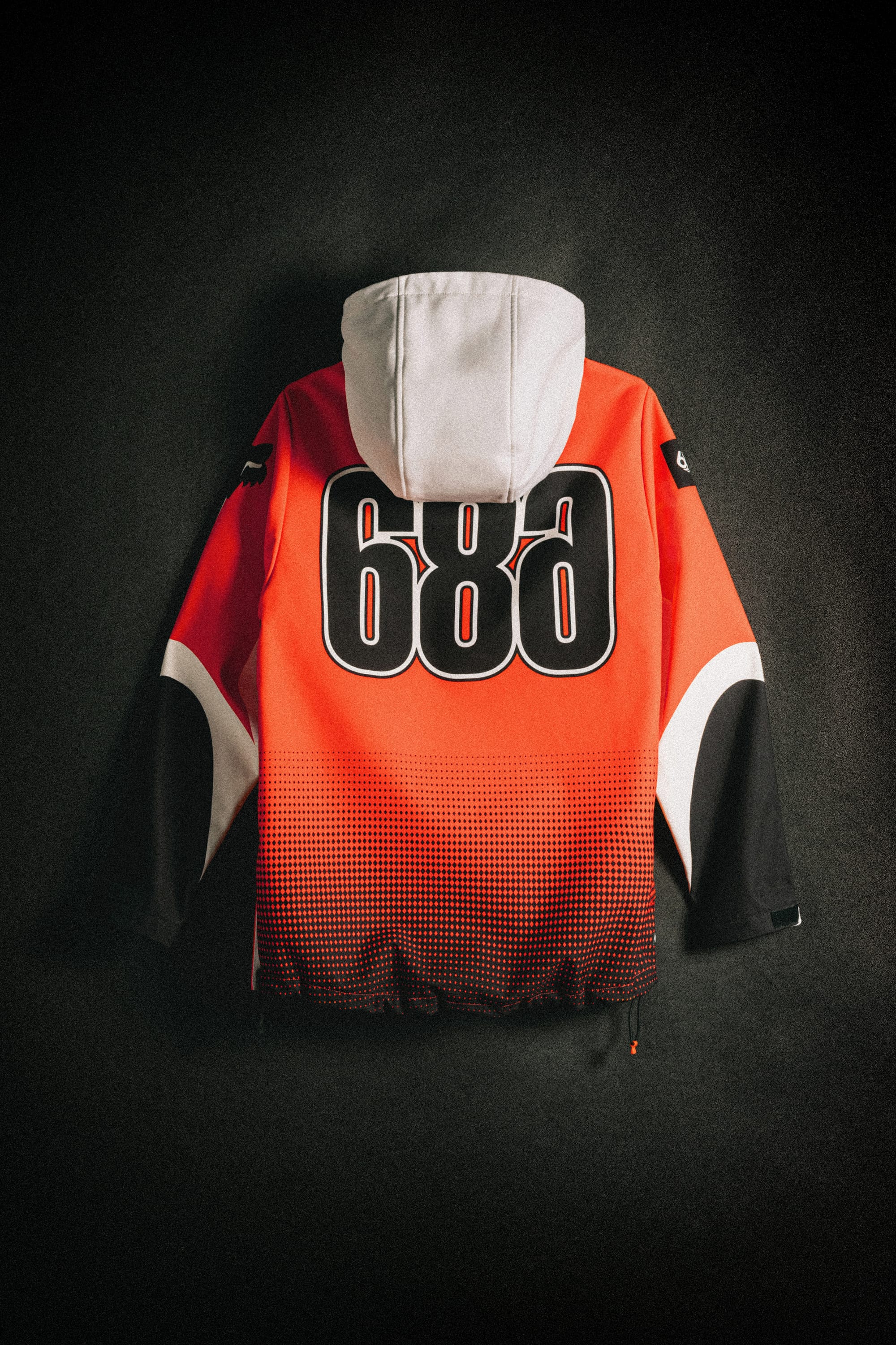 The 686 Women's Fox Racing 97 Waterproof Hoody by 686 is shown on a dark background. It features sporty red, black, and white colors, a large white hood, bold "688" graphics across the back, and dynamic graphic accents.