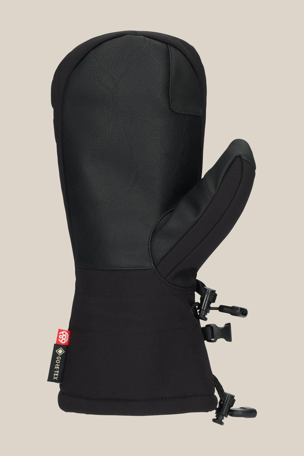 The 686 Men's GORE-TEX Linear™ Mitt features a black leather-like PU exterior, adjustable wrist straps, and a side fabric tag with the red and yellow 686 logo, shown against a plain beige background.