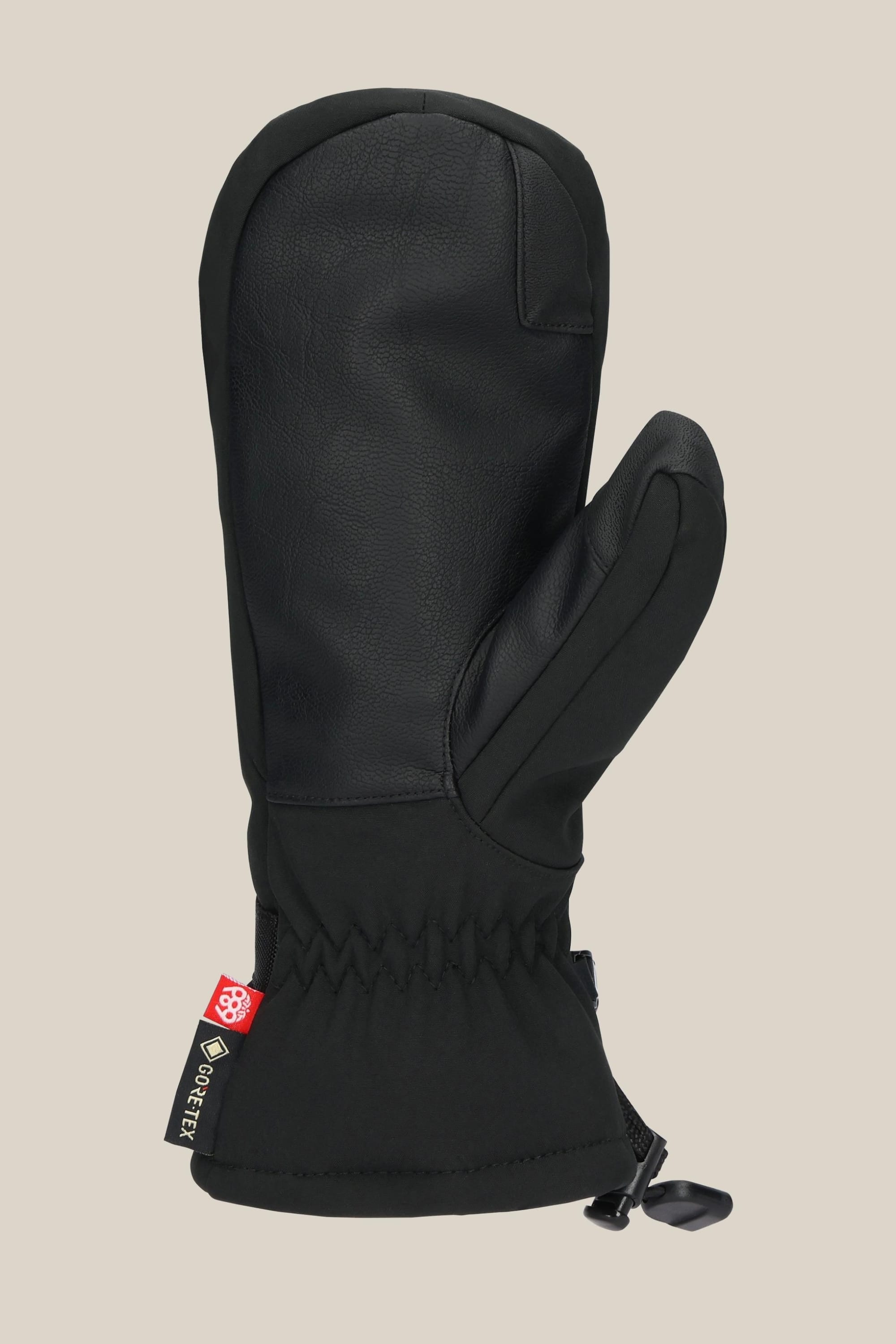 The 686 Women's GORE-TEX Linear™ Mitt in black, made from leather, poly, and PU fabric, has a cinched wrist, cuff drawstring, and GORE-TEX tag on the side. It's shown solo against a plain beige background.