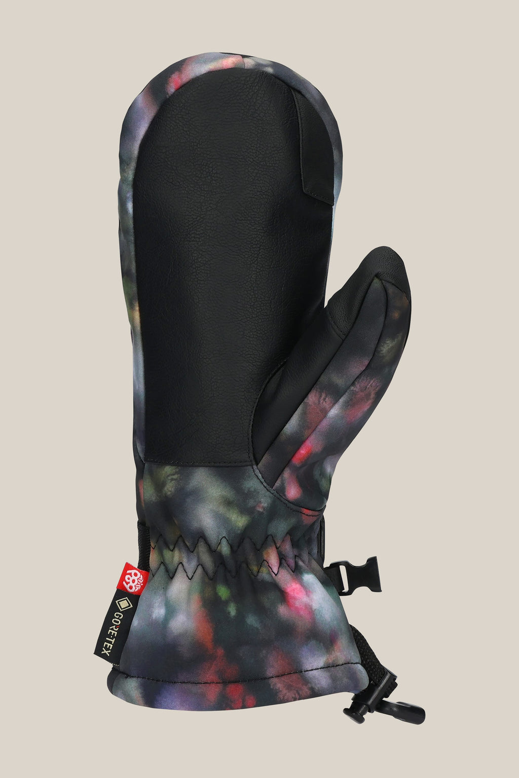 The 686 Women's GORE-TEX Linear™ Mitt features a black PU leather palm, vibrant tie-dye poly back, wrist strap, and small black buckle for a secure fit.