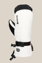 The 686 Women's GORE-TEX Linear™ Mitt features a white shell, black thumb, strap, and buckle, plus the 686 logo near the cuff. Made of poly and PU, it's shown against a light beige background.