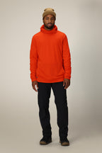 A man wearing a tan beanie, black pants, brown shoes, and a 686 Men's Mission Grid™ Fleece Hoody by 686 stands facing forward against a plain, light gray background.